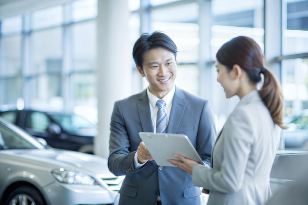 車の購入を検討している人が、自動車販売店のスタッフに相談している場面