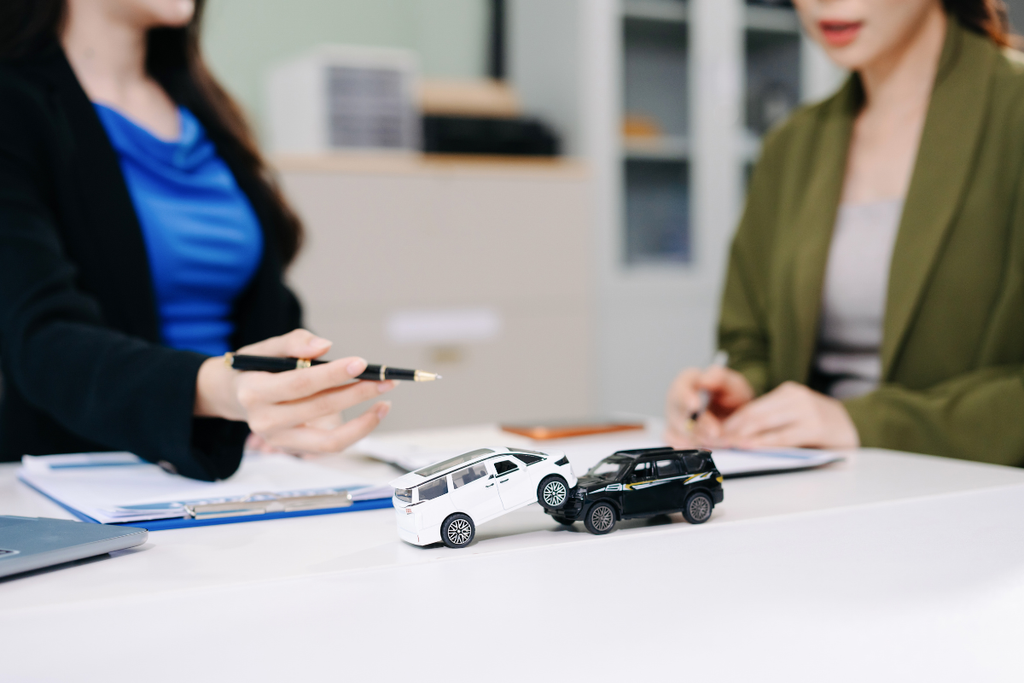 自宅や相談スペースで、給与明細・書類・電卓などを確認しながら車のローンについて考えている人物。