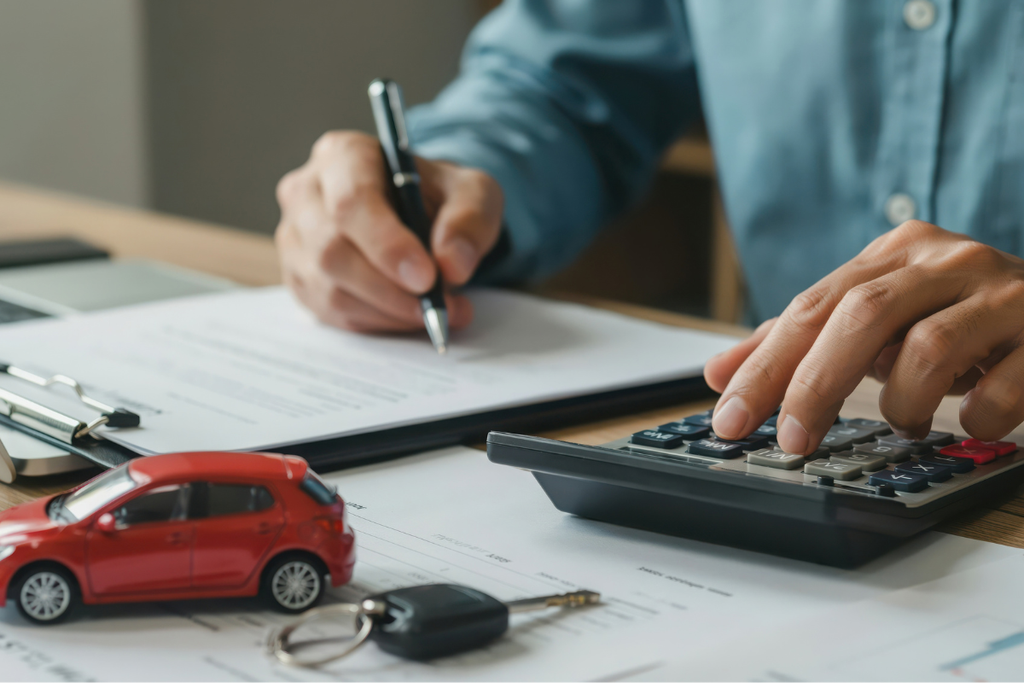 車の購入を検討しながら、電卓やスマートフォン・ノートなどで月々の支払いを計算している人物。