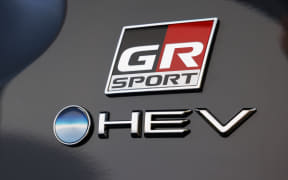 GR SPORT badge with red and black logo and HEV emblem on a dark car panel.