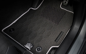 Close-up of a car's front interior floor mat in a dark, carpeted area.