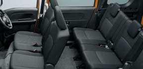 Interior of a vehicle showing two rows of black seats with orange door frames and gray floor mats