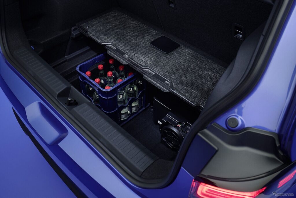 Blue car trunk with a blue crate holding glass bottles with red caps stored under a folded cargo cover in the back.